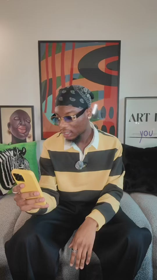 A stylist sitting down with a black and yellow stripe shirt and hat.
